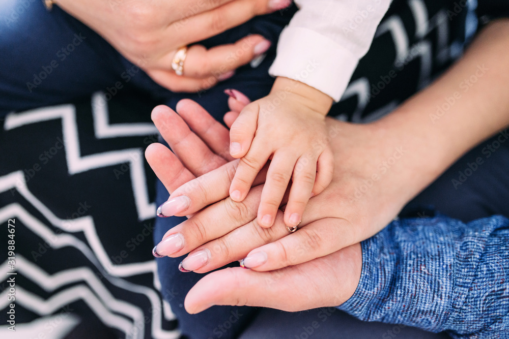 The concept of a friendly and happy family. Hands of mom, dad and baby closeup