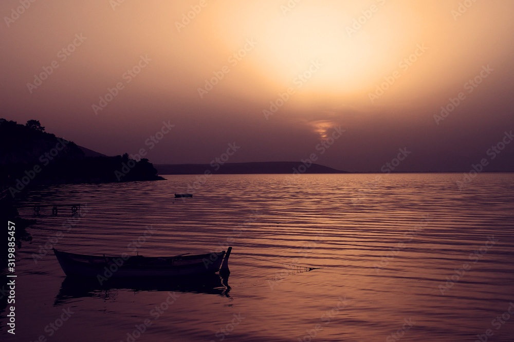 calm landscape with a lake and sunset and a boat