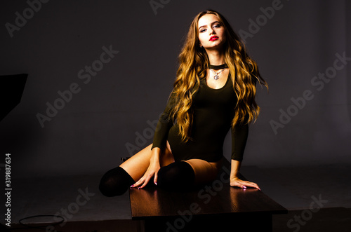 Beautiful dancer. Girl model. the girl sits in a hat and sits on a table. girl in a beautiful underwear. the girl is sitting on the table and fooling around, making faces. smooth, well-groomed legs