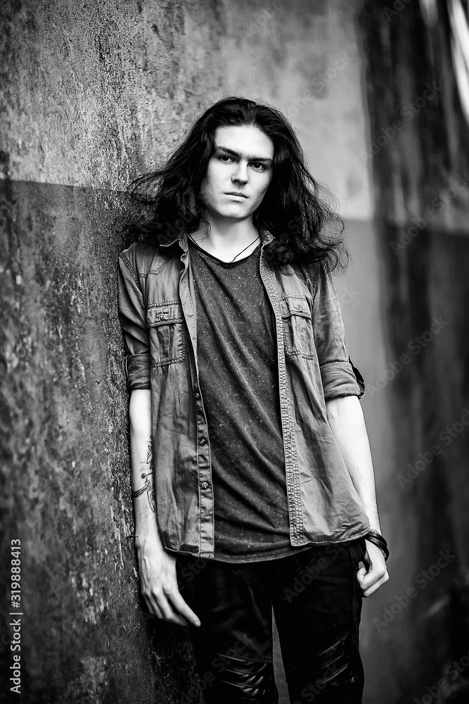 a black-and-white photo of a young man with long, dark hair and brown eyes, a face with freckles, walking down the street in a stylish shirt and jeans,in a Cagle style, in a sad mood a black-and-white photo of a young man with long, dark hair and brown eyes, a face with freckles, walking down the street in a stylish shirt and jeans,in a Cagle style, in a sad mood