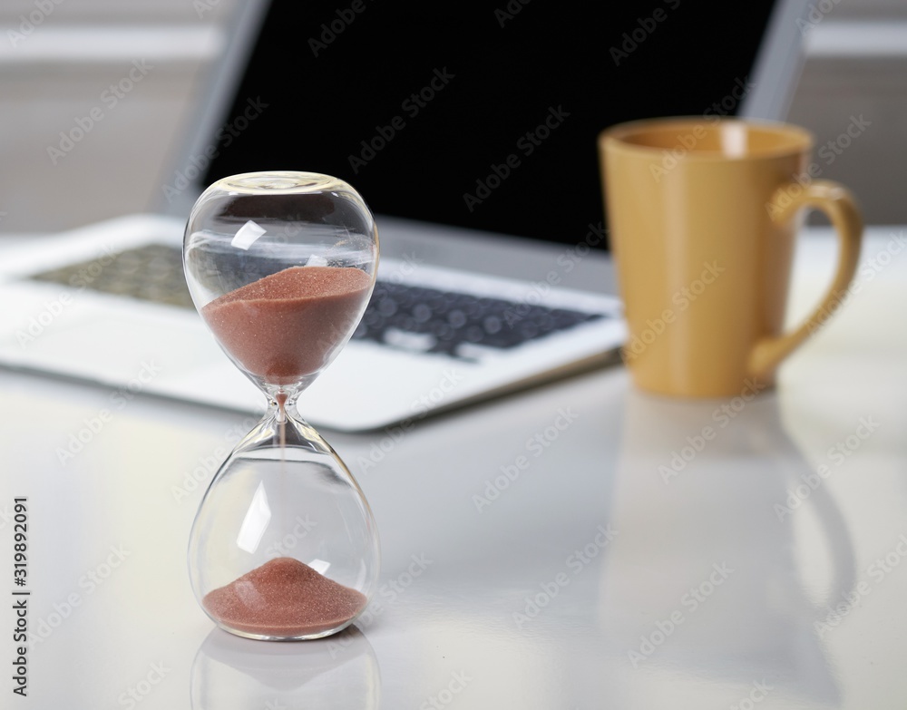 Hourglass on office desktop. Hourglass on office desktop.