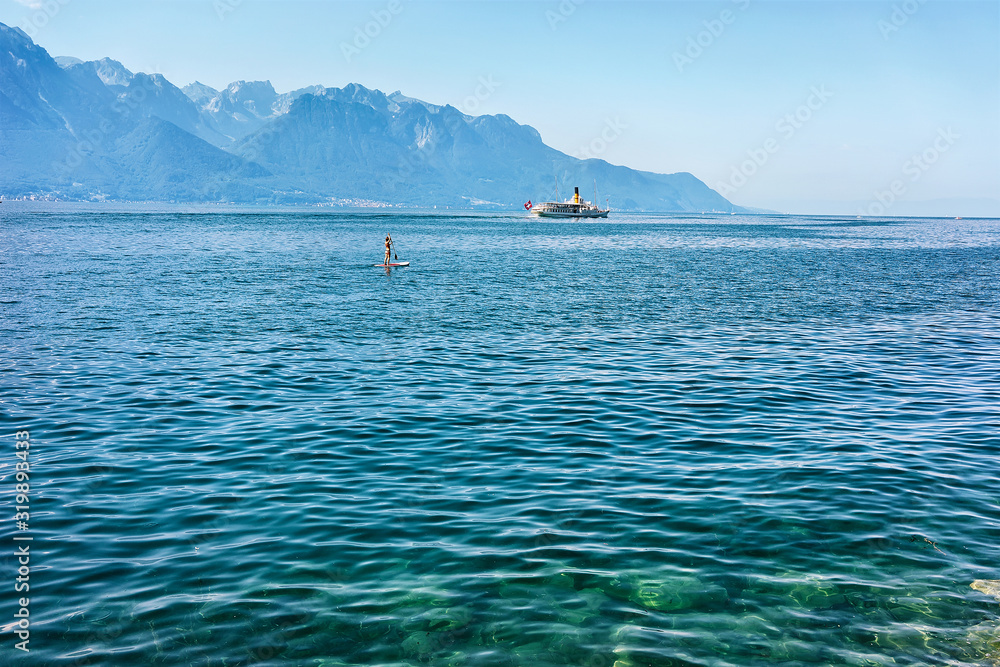 Surfer on stand up paddle board and Excursion ship on Geneva Lake of Montreux, Swiss Riviera Surfer on stand up paddle board and Excursion ship on Geneva Lake of Montreux, Swiss Riviera
