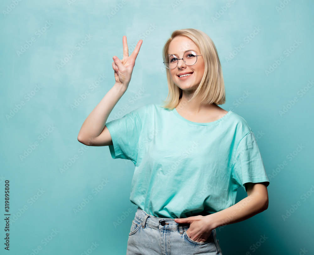 Style blonde woman in glasses show OK gesture on blue background Style blonde woman in glasses show OK gesture on blue background