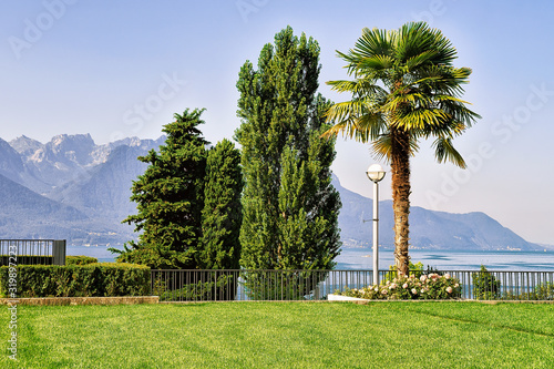 Garden at Geneva Lake in Montreux, Swiss Riviera. Alps mountains on the background