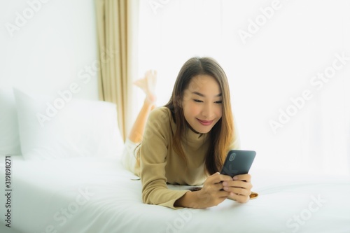 Young asian woman using mobile smart phone on bed