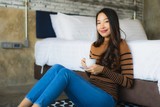 Young asian woman with coffee cup on bed