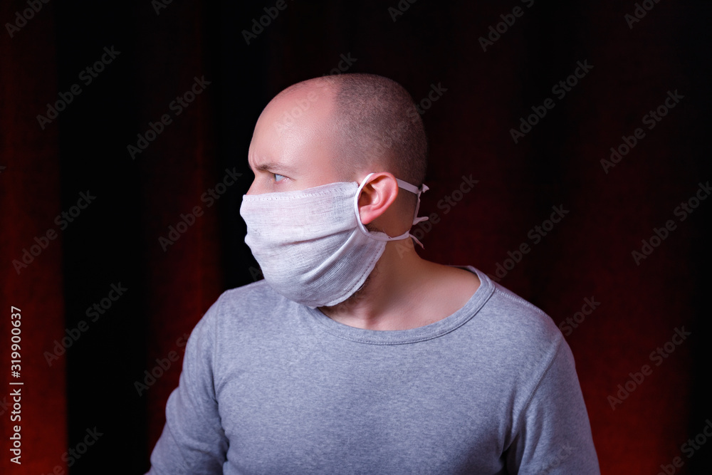 Profile of a man in medical gauze mask standing on dark red background ...