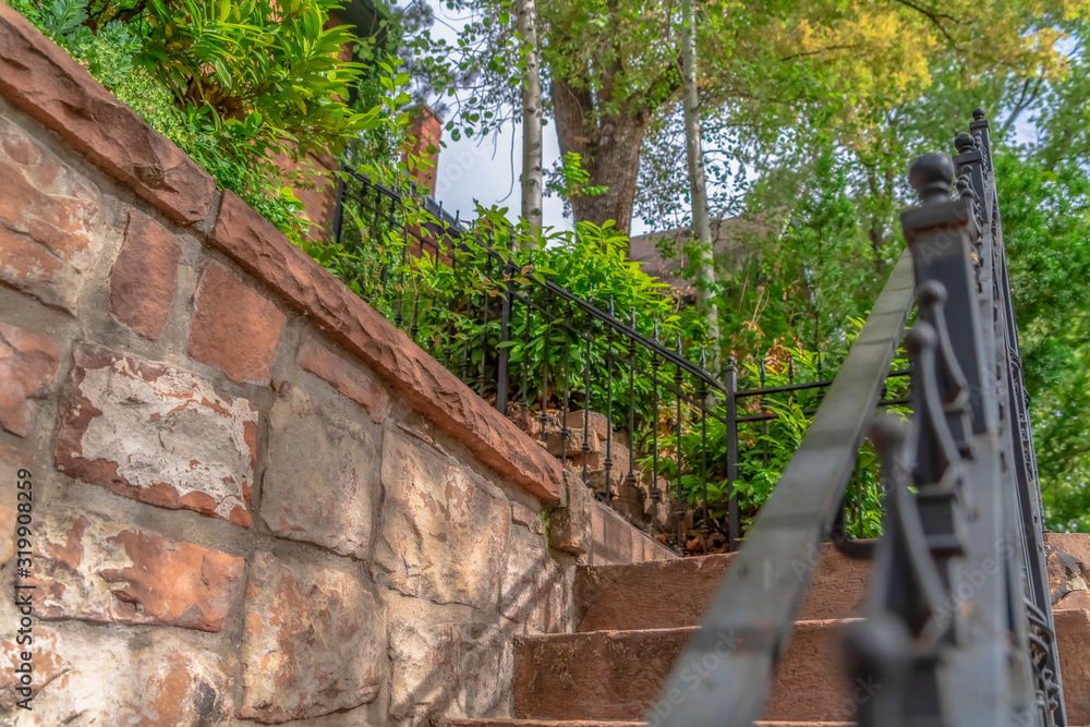 Fototapeta premium Close up of outdoor stairs with black metal handrail against a stone wall
