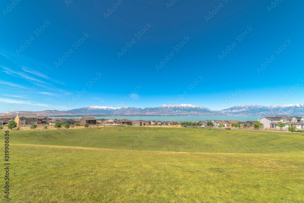 Obraz premium Golf course blanketed with vibrant green grasses overlooking homes and lake