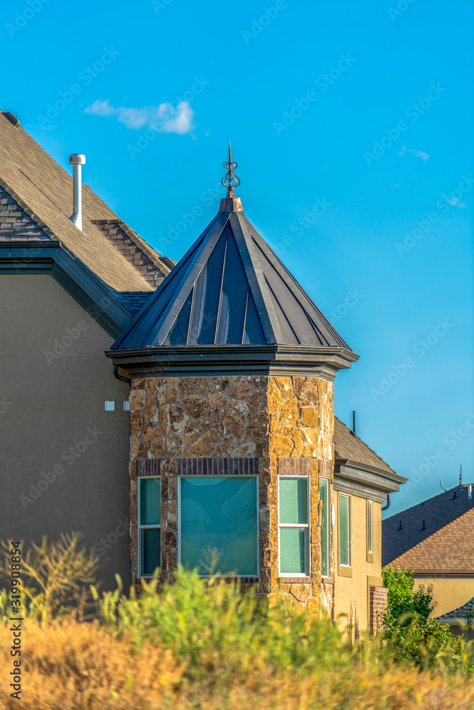 Exterior of home with bay window under gray hip roof against blue sky