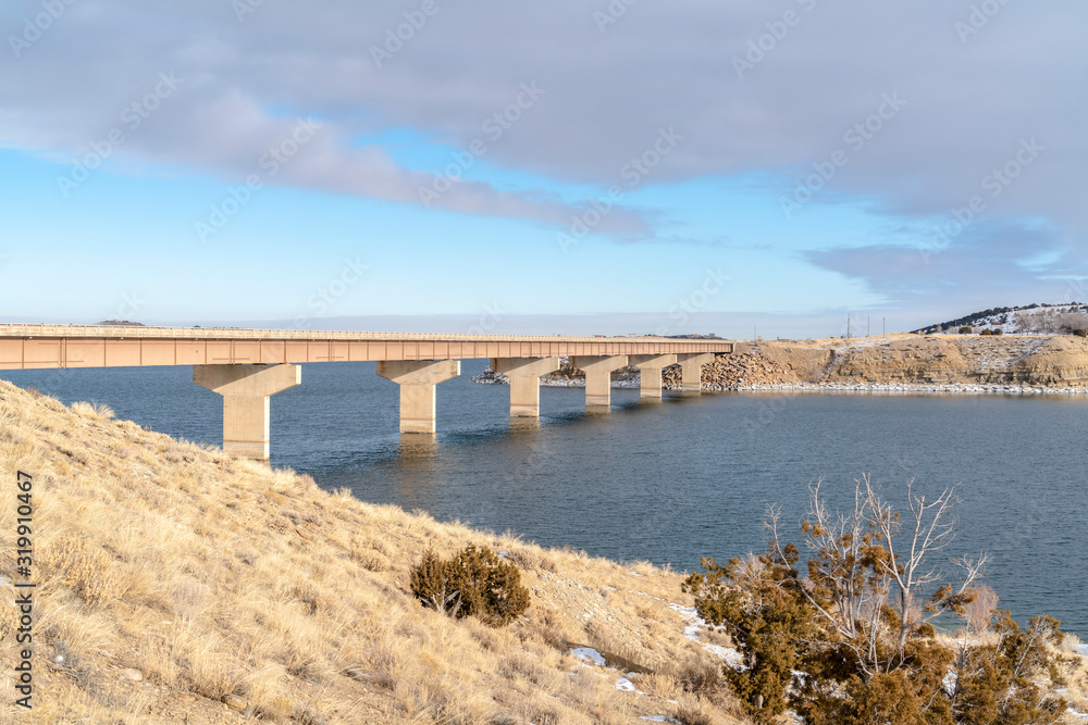 Grassy mountain overlooking a bridge over blue lake on a cold winter day Grassy mountain overlooking a bridge over blue lake on a cold winter day
