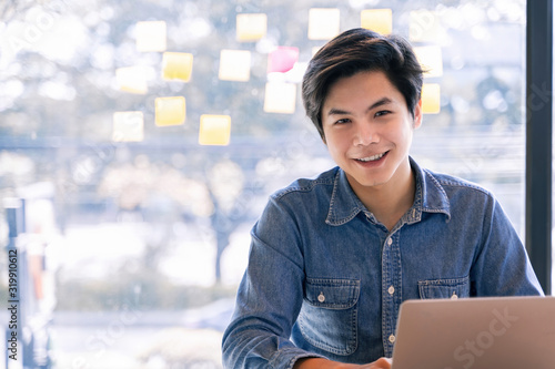 Принти на полотні Confident asian business male smiling and look at camera while working on laptop computer at office