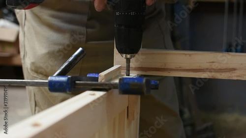 close up wood worker tightens the screw with a screwdriver in a wooden structure