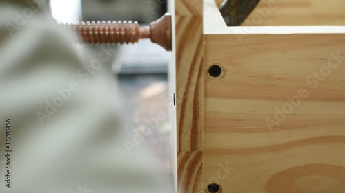 close up wood worker tightens the screw with a screwdriver in a wooden board