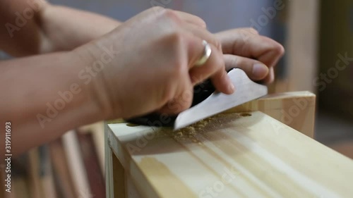 close up woman carpenter using a little wood planer on a wood box