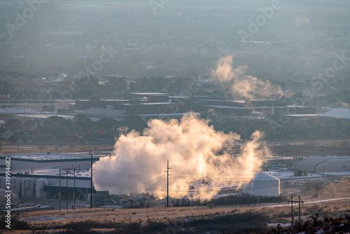 Industrial plant emitting thick smoke against foggy landscape in winter