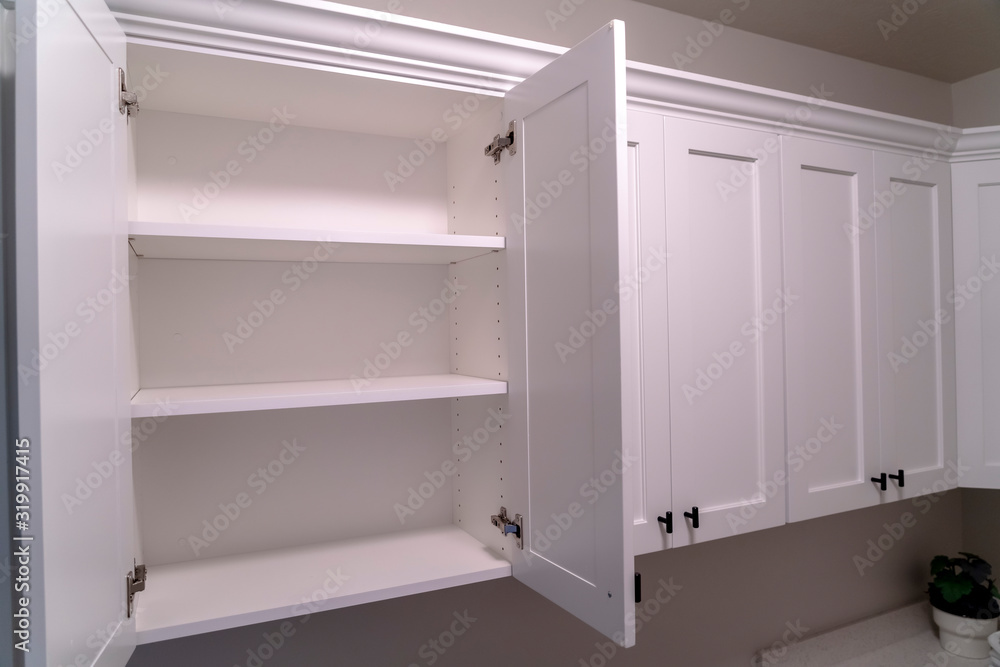 Open wooden cabinet with decorative moulding and black handle mounted on wall Open wooden cabinet with decorative moulding and black handle mounted on wall