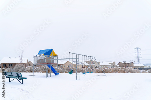 Neighborhood park with vibrant playground that contrasts against snow in winter