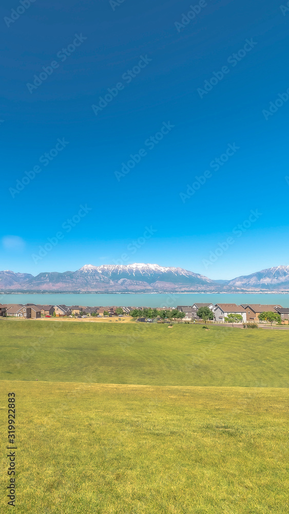 Vertical frame Golf course blanketed with vibrant green grasses overlooking homes and lake Vertical frame Golf course blanketed with vibrant green grasses overlooking homes and lake