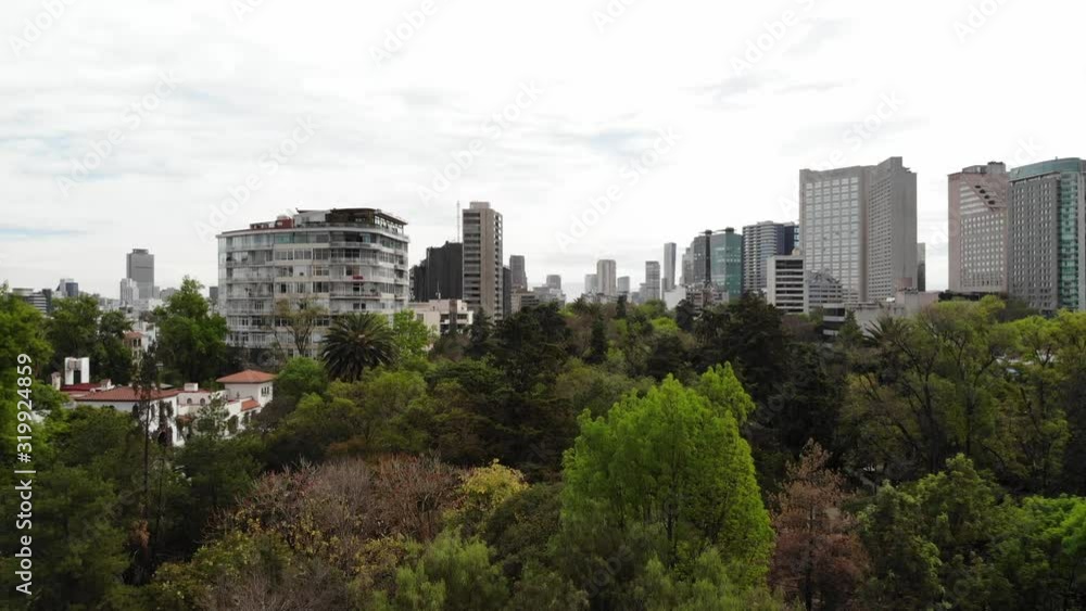 Revealng the skyline of Polanco, drone slowly ascending over Parque Lincoln on a cloudy day Revealng the skyline of Polanco, drone slowly ascending over Parque Lincoln on a cloudy day