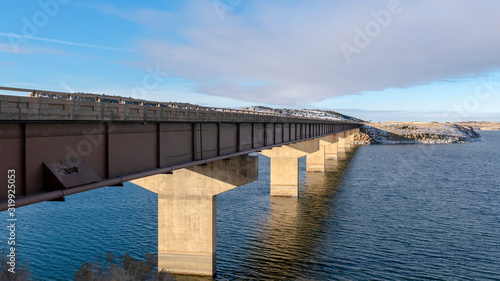 Panorama Bridge over a vast calm lake with snow covered shore during winter season