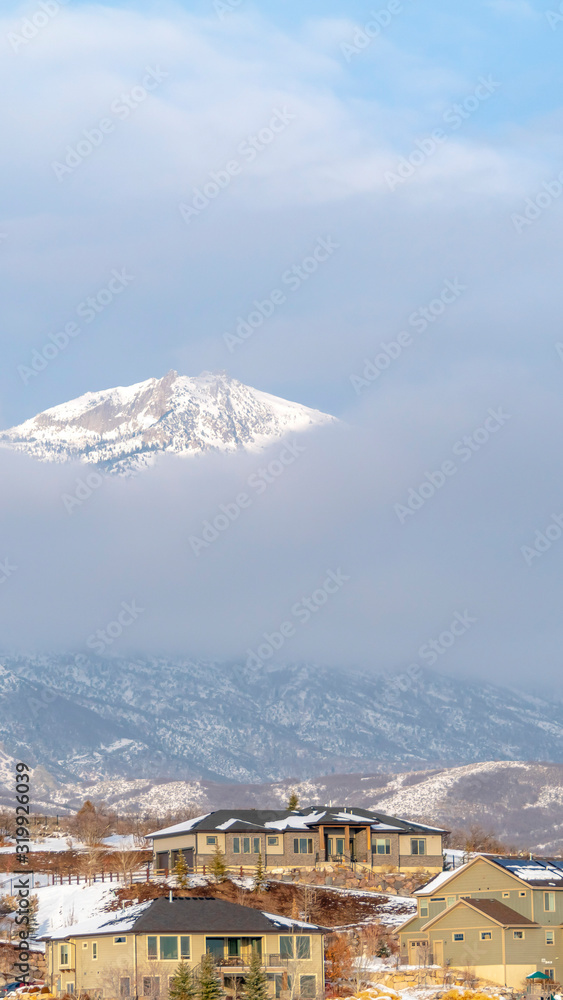 Photo Vertical frame Houses with view of a snowy mountain peak against thick clouds in winter