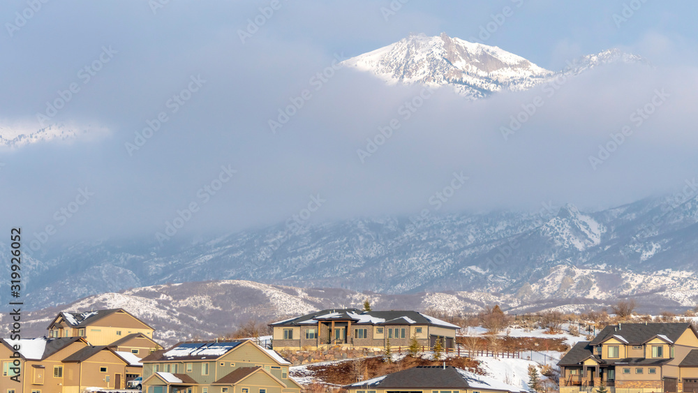Photo Panorama Houses with view of a snowy mountain peak against thick clouds in winter