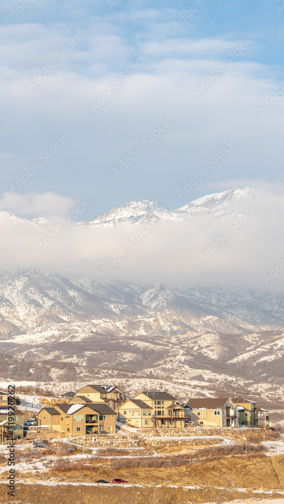 Photo Vertical frame Houses with view of snowy mountain partially covered by clouds in winter