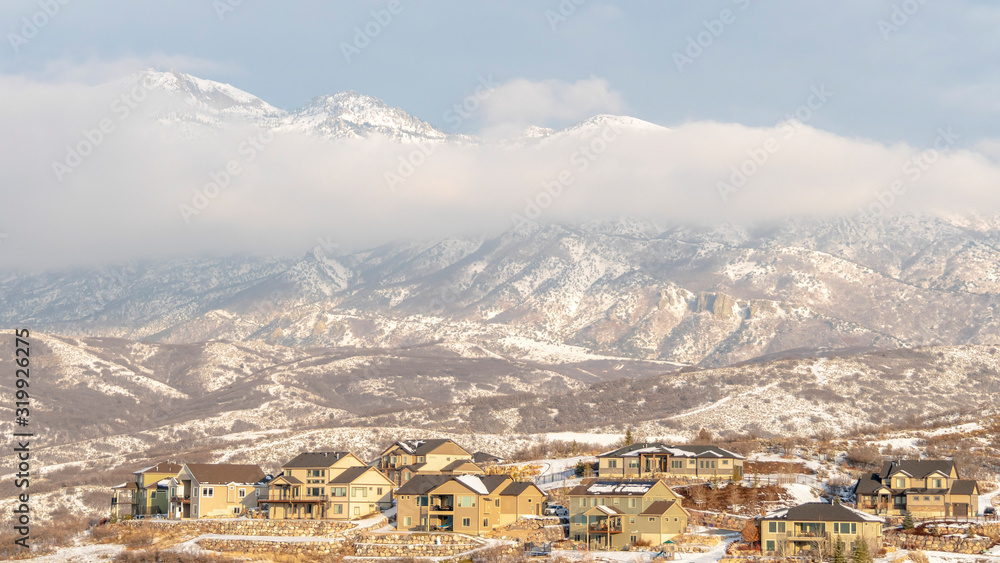 Panorama Houses with view of snowy mountain partially covered by clouds in winter