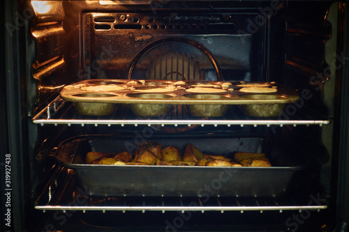 Fototapeta Naklejka Na Ścianę i Meble -  View through oven window of cooking roast potatoes and Yorkshire puddings                  