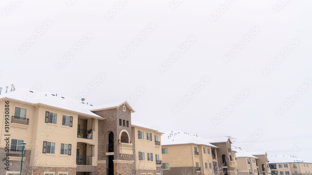 Panorama Facade of homes with snow coated roofs against cloudy sky on a cold winter day