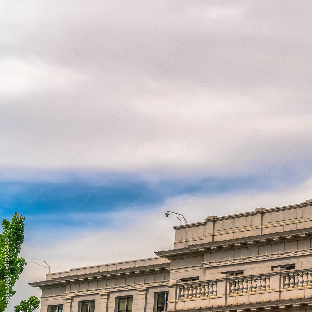 Square Building with white wall balcony and security camera on roof against cloudy sky Square Building with white wall balcony and security camera on roof against cloudy sky