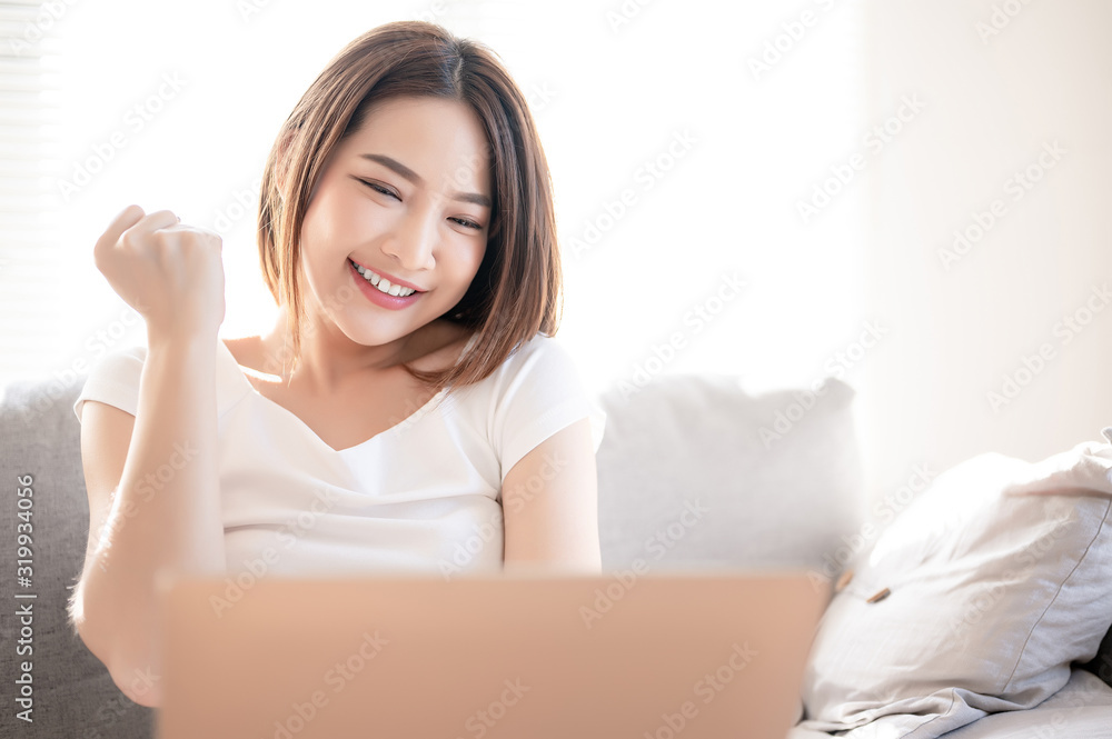 Asian woman glad with something in her laptop in the living room. Asian woman glad with something in her laptop in the living room.