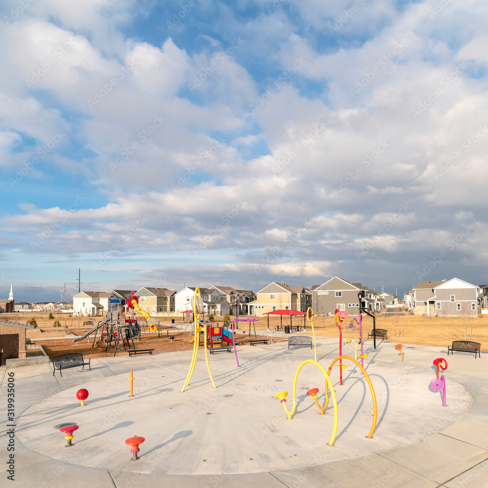 Fototapeta premium Square frame Colorful childrens playground against houses and overcast blue sky in winter