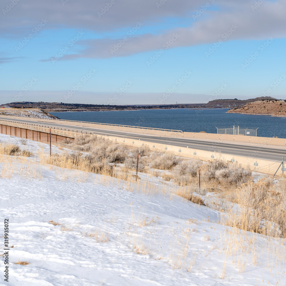 Square Snow covered terrain along a road overlooking mountain and lake in winter Square Snow covered terrain along a road overlooking mountain and lake in winter