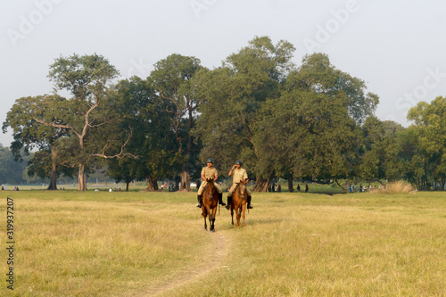 Kolkata Mounted Police personnel keep galloping in style, vigilance and patrolling Maidan area of Brigade Parade ground in Summer sunset time. Eden Gardens, Kolkata City, West Bengal, India, May 2019