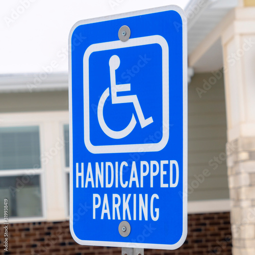 Square Handicapped Parking and Van Accessible sign against snow and building in winter
