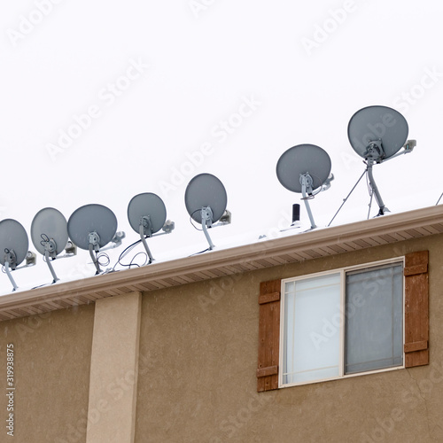 Square frame Bowl shaped antennas mounted on the snowy roof of residential building in winter photo