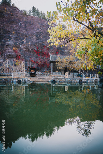 Dock by the river in Beijing Wtown（Gubei Water Town）. Fishing boat moored by a river full of autumn leaves photo