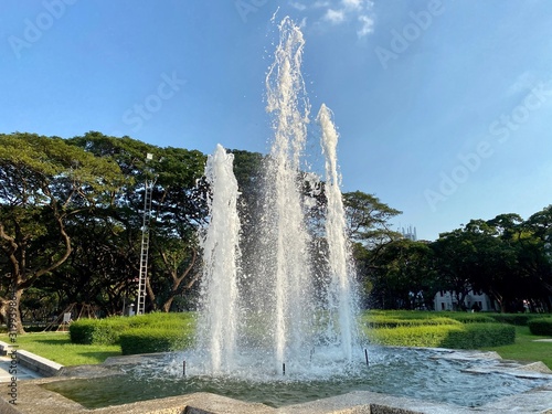 Fountain water in the park with blue sky and tree in Thailand
