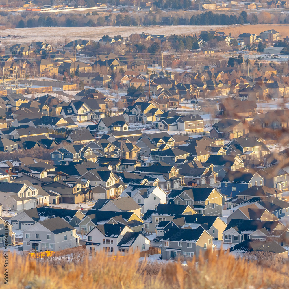 Obraz premium Photo Square frame Neighborhood landscape nestled amid hilly terrain blanketed with snow in winter
