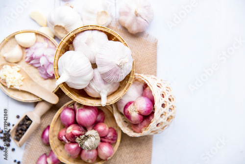Garlic,shallot,Black pepper, fresh garlic, garlic clove, garlic bulb andshallot in a wooden basket on white wooden table, A herb and spice cloves or food ingredients, Place for text.