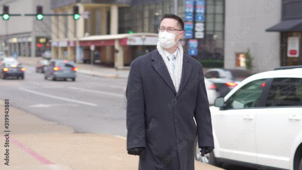 Young man with face mask on in city downtown during the day because of the flu virus and trying to protect himself from contagious diseases Young man with face mask on in city downtown during the day because of the flu virus and trying to protect himself from contagious diseases