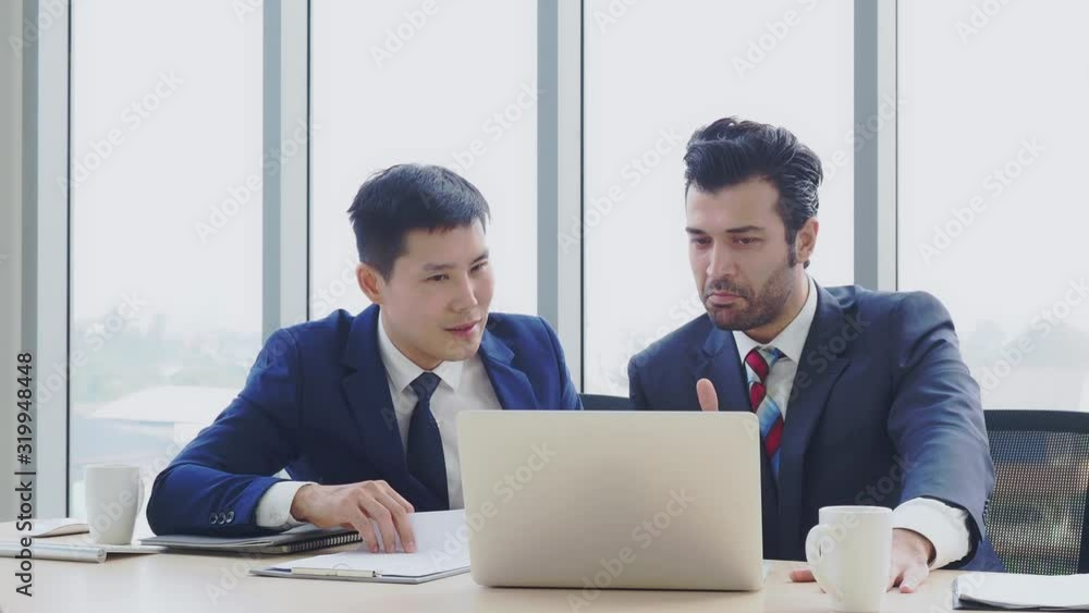Two businessman talking together and looking laptop on table at meeting room. Teamwork, partnership concept Two businessman talking together and looking laptop on table at meeting room. Teamwork, partnership concept