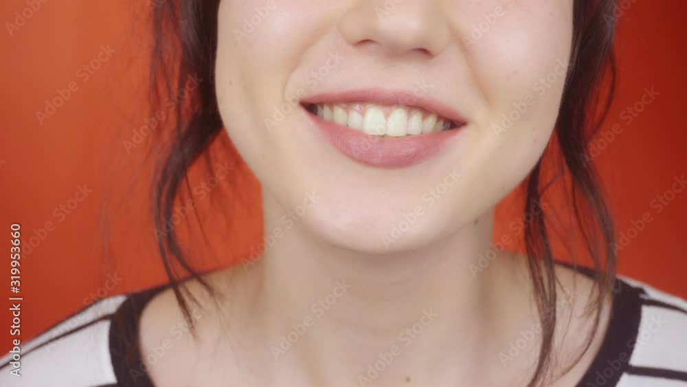 Young happy woman smiles at the camera on a red background. Close-up. Young happy woman smiles at the camera on a red background. Close-up.