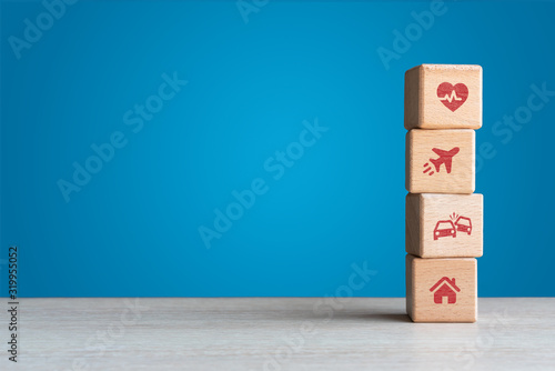 Travel medical car and home insurance icons on wood blocks concept with blue backdrop 