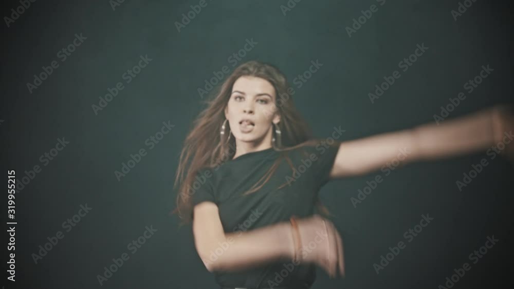 A young attractive woman with long hair walking out from the smoke in the studio and standing in the pose A young attractive woman with long hair walking out from the smoke in the studio and standing in the pose