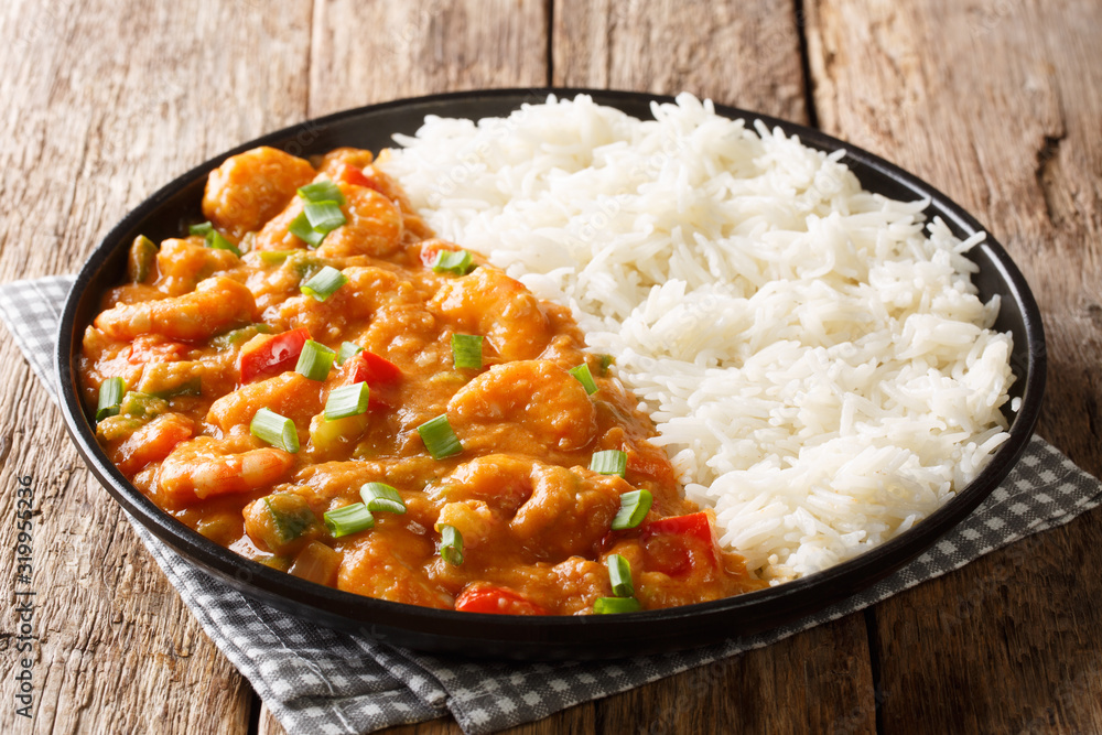 Serving of shrimp Etouffee with vegetables and sauce served with rice closeup in a plate. horizontal
