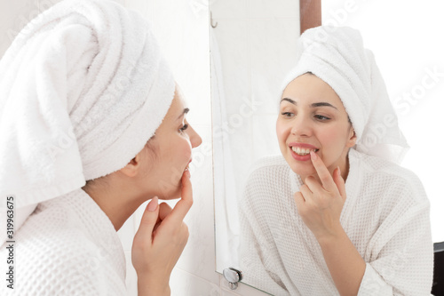 Morning hygiene routine. Pretty woman looking in the mirror on her teeth after washing and cleansing.