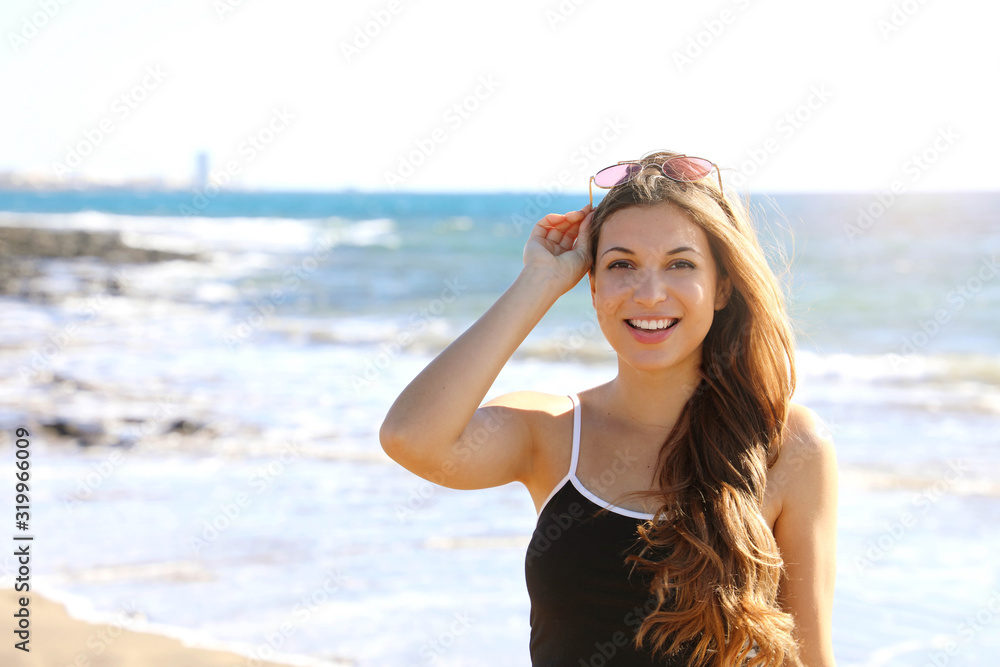 Pretty modern sporty woman with sunglasses on her head looking happy smiling at camera on the beach Pretty modern sporty woman with sunglasses on her head looking happy smiling at camera on the beach
